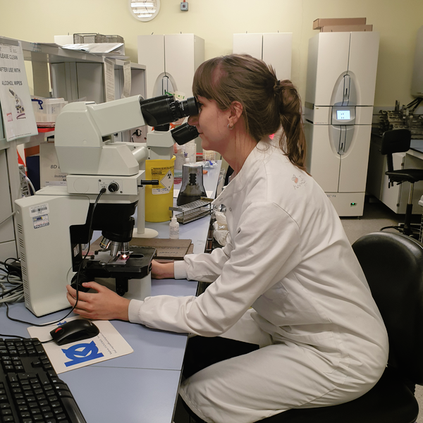 Dr Francesca Heard looking down a microscope