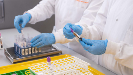 2 people in white lab coats sorting virology sample tubes