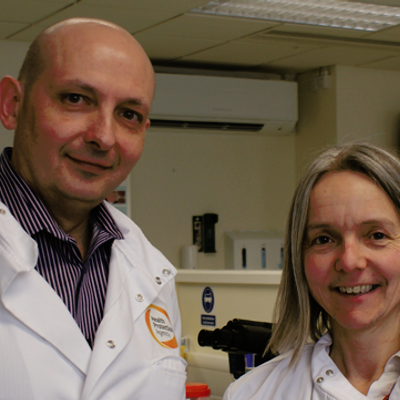 Fiona Cooke and Oleg Tkachenko smiling at the camera in a laboratory