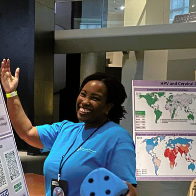 Dr Angeli Arthur smiling alongside their poster