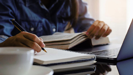 Student handwriting information on diary notebook while reading book
