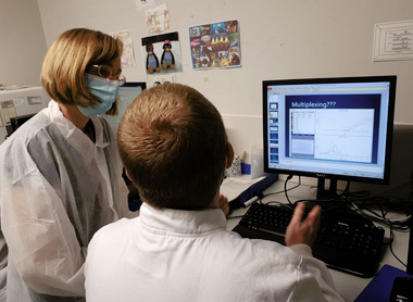 Dr Louise Berry talking to a colleague at a computer screen