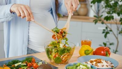 Person serving a salad in a kitchen