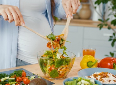 Person serving a salad in a kitchen