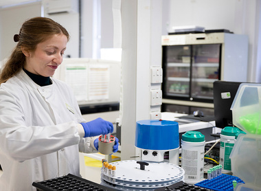 Biomedical scientist putting samples in a machine in a blood sciences lab