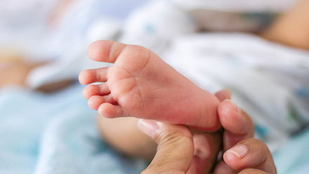 Person holding a baby's foot