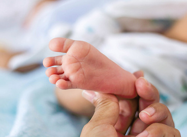 Person holding a baby's foot