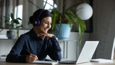 Person sitting at desk on laptop writing notes