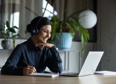 Person sitting at desk on laptop writing notes