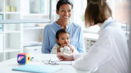 Smiling person with baby sitting on their lap at appointment