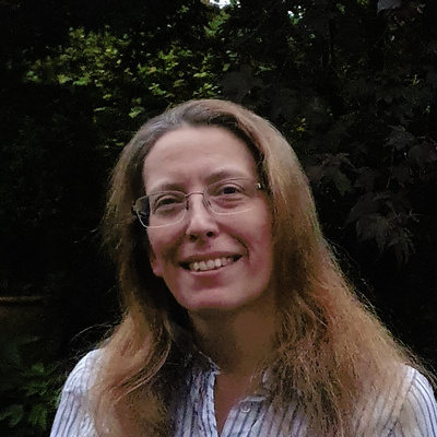 Dr Lucy Leeman in front of trees smiling at the camera