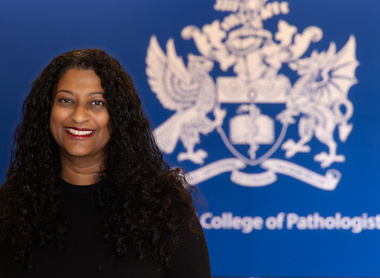Dr Natasha Ratnaraja smiling in front of a Royal College of Pathologist banner at an event