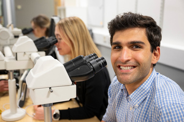 Smiling cellular pathology year 1 specialty trainee at a microscope