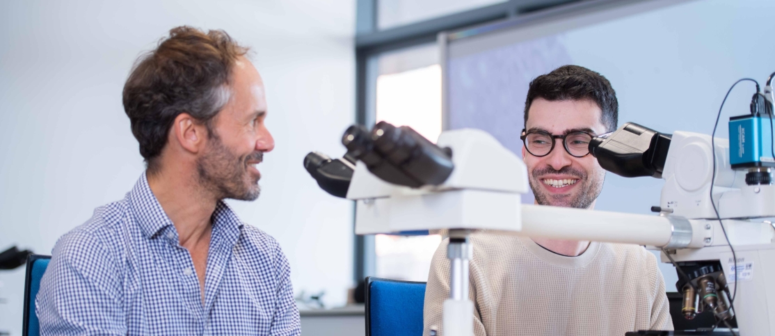 Students at the Royal London Hospital, laughing next to a microscope