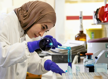 Scientist pouring blue reagent into test tube