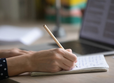 Person writing an essay on lined paper