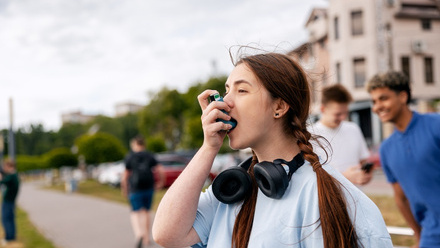 Young woman administering medicine with an inhaler