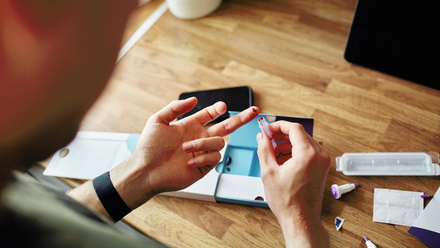 Person pricking their finger to use blood for point-of-care testing
