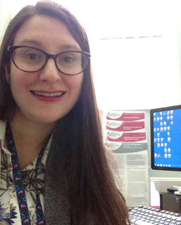 Dr Kate Earp smiling at the camera while sat at their computer