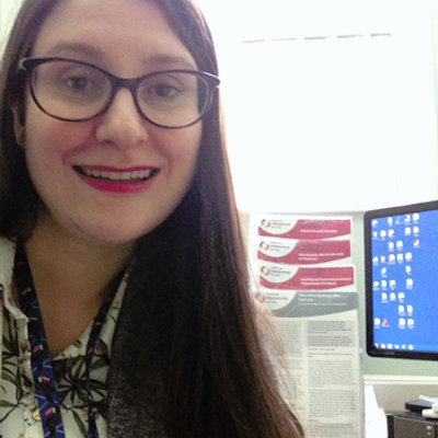 Dr Kate Earp smiling at the camera while sat at their computer